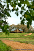 Exterior, vertical, rear elevation scene setter with dirt road and farm fields in the foreground, DeSocio residence, Henry, Tennessee, Honest Abe Log Homes